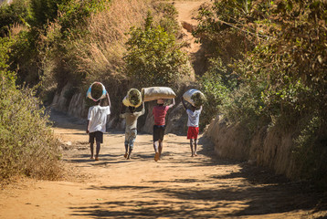 Fototapeta premium four people walk with bags full of family and pet food on their heads