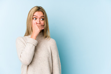 Young blonde caucasian woman isolated thoughtful looking to a copy space covering mouth with hand.