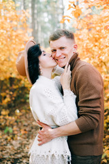 two happy lovers embrace each other in the middle of a pine forest in the autumn, around the Golden leaves on the trees