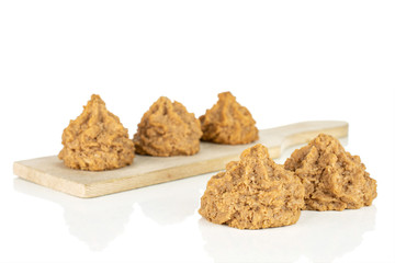 Group of five whole homemade brown coconut biscuit with chocolate on small wooden cutting board isolated on white background