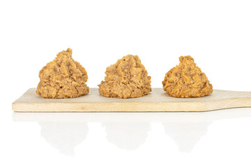 Group of three whole homemade brown coconut biscuit with chocolate on small wooden cutting board isolated on white background