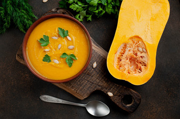 pumpkin cream soup with seeds and herbs on a stone background. healthy food.