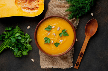 pumpkin cream soup with seeds and herbs on a stone background. healthy food.