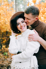 two happy lovers embrace each other in the middle of a pine forest in the autumn, around the Golden leaves on the trees