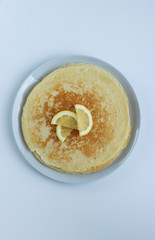 pancakes for Shrovetide with lemon on a white background, top view