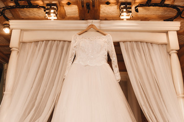 Fototapeta na wymiar The bride's wedding dress hangs on a wooden white bed