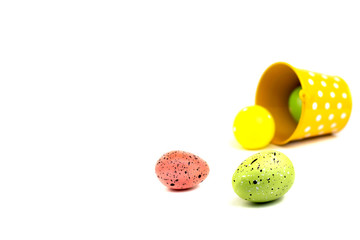 Colorful Easter eggs spilled from yellow bucket on white background.
