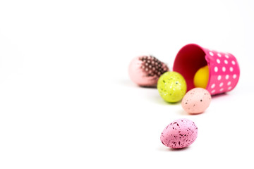 Colorful Easter eggs spilled from yellow bucket on white background.