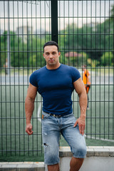 Sports guy stands near the sports field. Bodybuilding