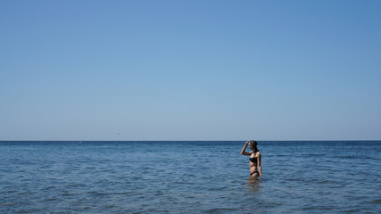 Fototapeta na wymiar Young woman in a swimsuit and with a mask for snorkelling in the Black Sea in Russia.