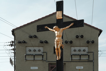 A crucifix  - golden sculpture of Jesus Christ hanging on a wooden cross - in front of a...