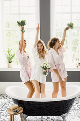 young beautiful blonde wedding bride in a beautiful white dress having fun with bridesmaids in the bathroom