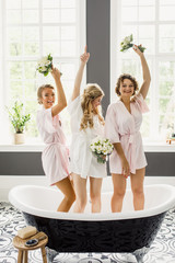 young beautiful blonde wedding bride in a beautiful white dress having fun with bridesmaids in the bathroom
