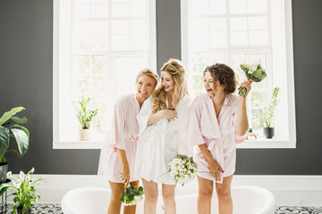 young beautiful blonde wedding bride in a beautiful white dress having fun with bridesmaids in the bathroom