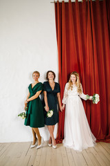 young beautiful blonde wedding bride in a beautiful white dress stands on a red background