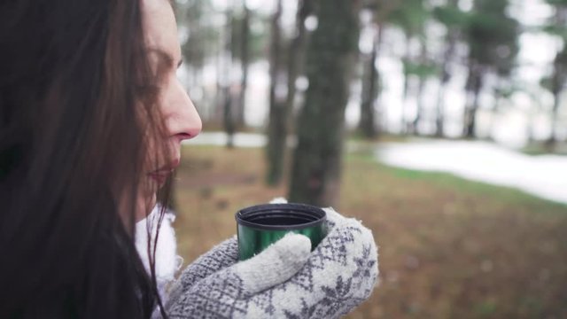 Woman drinking tea in the forest. The girl drinks tea from a thermos. Picnic in the woods. A woman walks in the winter forest. A walk in the woods. Magical forest. A girl in a fairy tale. F
