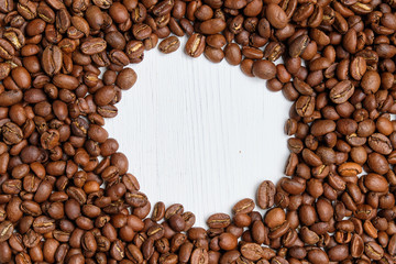 Coffee roasted grains on a white wooden background with a circle. Copy space.