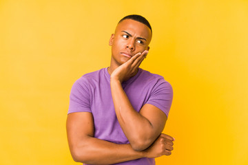 Young latin man isolated on yellow background who is bored, fatigued and need a relax day.