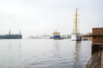 The embankment of the Neva with an icebreaker, a sailboat on a foggy spring warm day in April