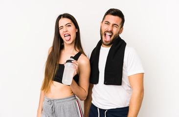 Young caucasian fitness couple isolated funny and friendly sticking out tongue.