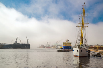 Fototapeta premium The embankment of the Neva with an icebreaker, a sailboat on a foggy spring warm day in April