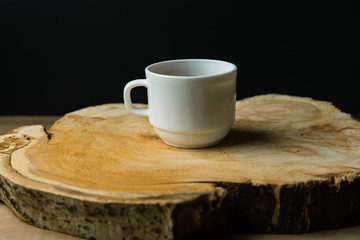 white cup with tea on a tree cut