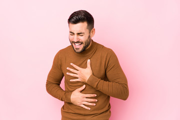 Young caucasian man against a pink background isolated laughs happily and has fun keeping hands on...