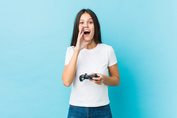 Young caucasian woman holding a game controller shouting excited to front.