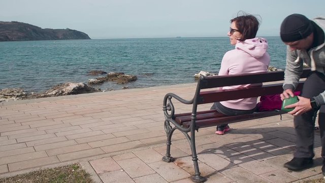 Robber pickpocket a wallet from a young attractive girl sitting on a bench on the beach watching ocean.