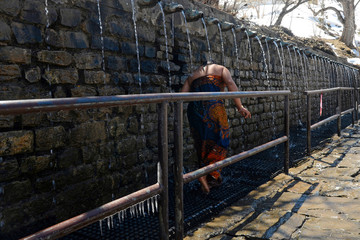 Pilgrim (woman) showering under the 108 holy taps. Muktinath temple, Mustang, Nepal.
