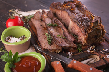 Fried meat. Beef steak on the bone with spices and sauce on a wooden cutting board. Close-up