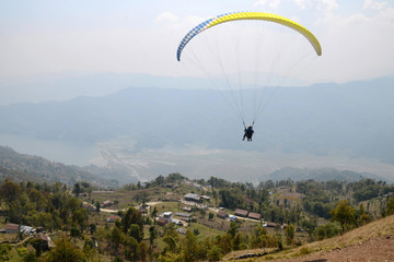 Paragliding in Nepal. Paraglider with tourist and instructor on the background of Phewa Lake and surrounding villages. Pokhara.
