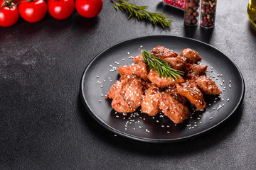 Chicken fillet in sesame seeds, teriyaki sauce on a black stone plate