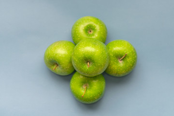 A bunch of beautiful green apples on an isolated blue background. Top view with copy space