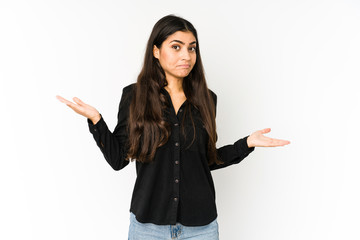 Young indian woman isolated on purple background confused and doubtful shrugging shoulders to hold...