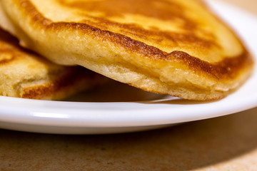Baked thick brown pancakes on a white plate on the table.