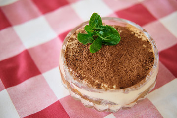 Classic tiramisu dessert in a glass on a red and white checkered background
