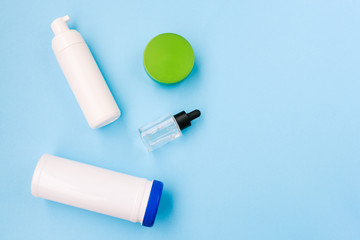 Cosmetic products on a blue background with copy space. Bottle for wet wipes, face cream, lotion and nail polish remover.