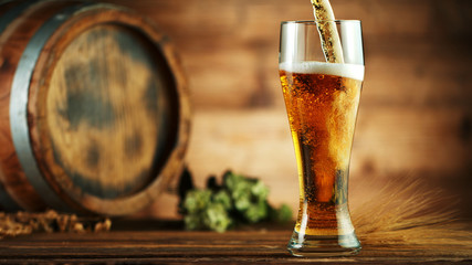 Pouring beer into glass pint, placed on wood