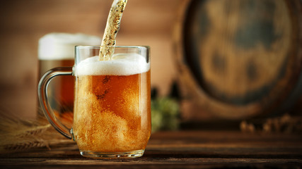 Pouring beer into glass pint, placed on wood