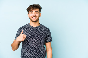 Young arabian man isolated on a blue background smiling and raising thumb up