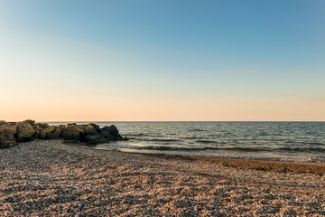 Empty sandy beach in Peresyp resort village. Evening sea landscape. Stacked stone boulders....