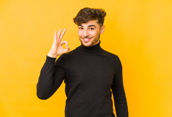 Young arabian man isolated on a yellow background cheerful and confident showing ok gesture.