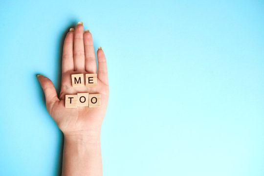 Phrase Me Too made of wooden letters in hand on blue background, top view. Stop sexual assault. Space left for text, copy