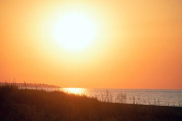 Evening sea landscape with low big sun on horizon. Orange sunset close-up.