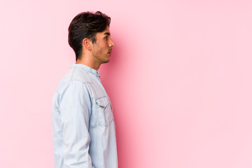 Young caucasian man posing in a pink background isolated gazing left, sideways pose.