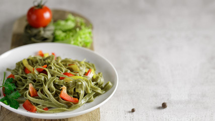 Boiled fettuccine with spinach seasoned with spices and vegetables on the table. Selective focus