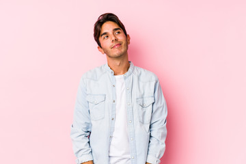 Young caucasian man posing in a pink background isolated dreaming of achieving goals and purposes