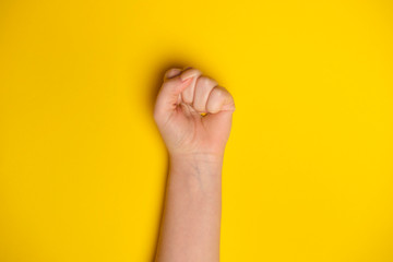 Naklejka premium Woman fist as symbol of protest shot on yellow bee background. Woman rights equality concept