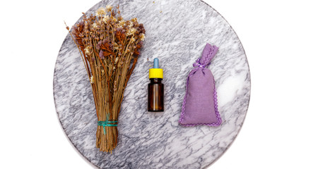 Essential oil and lavender flowers. Selection of essential oil on marble tabel with various organic herbs and flowers in the background.